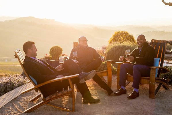 Men sitting in chairs with red wine