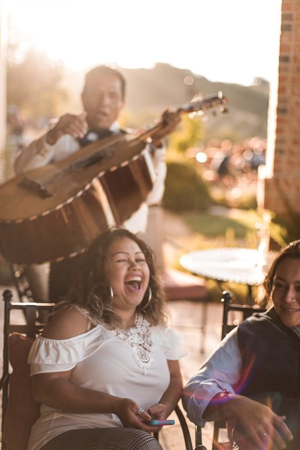 Women laughing in front of a mariachi band
