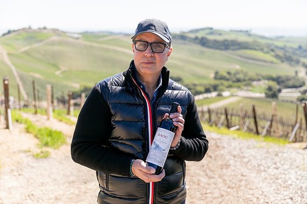 Daniel Daou poses in the vineyards with a bottle of Eye of the Falcon