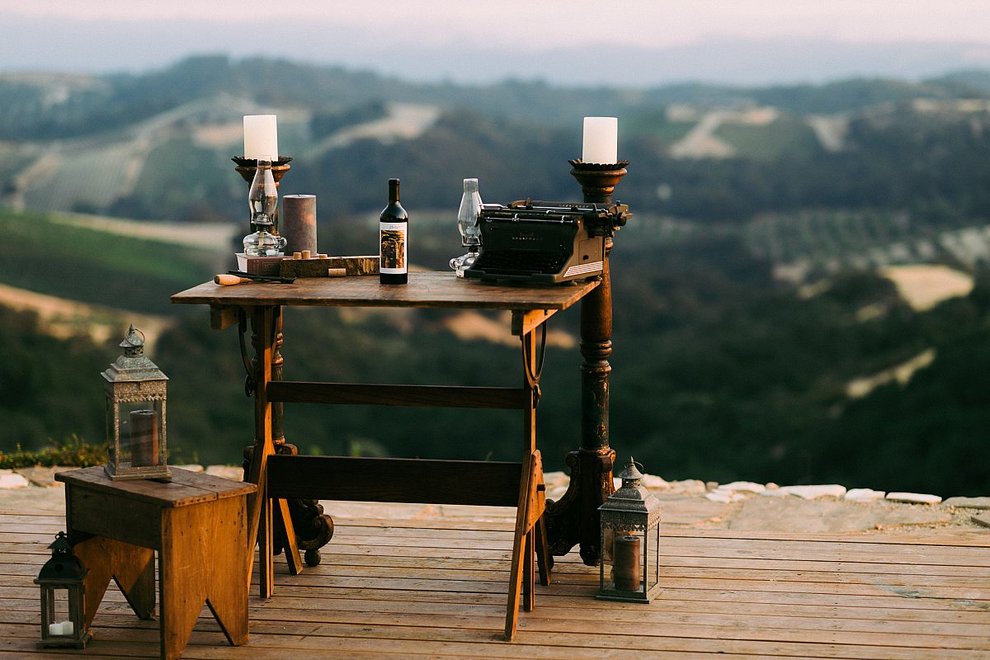 An antique desk with candles and abottle of wine overlooks the mountains