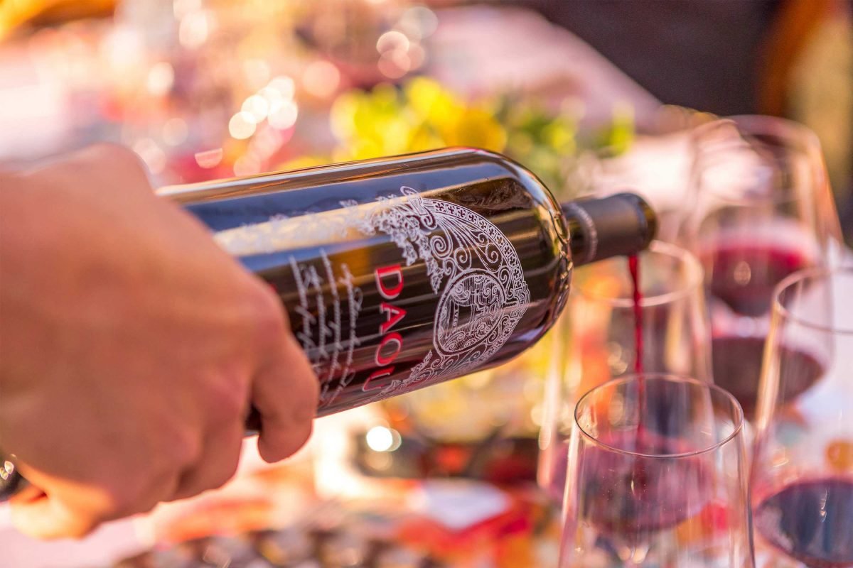 A large format bottle of wine being poured into a glass on a table