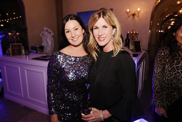 Two women pose at a wine event