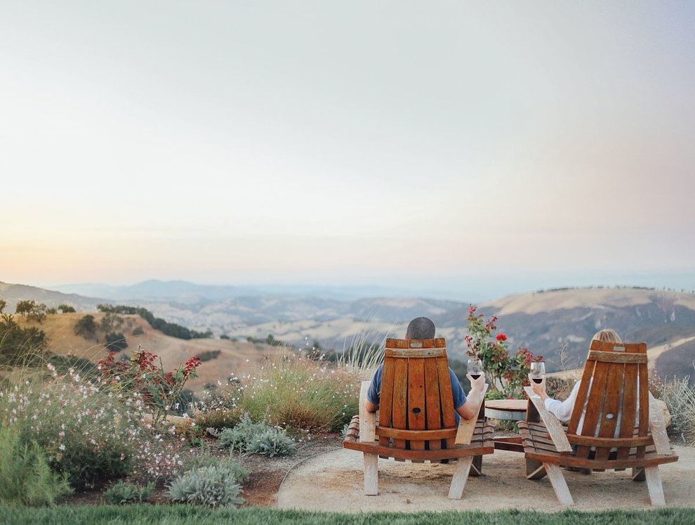 A couple sits in Adirondack chairs overlooking the mountains