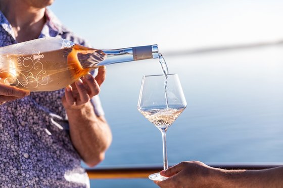 A person pours a bottle of DAOU rosé into a wine glass