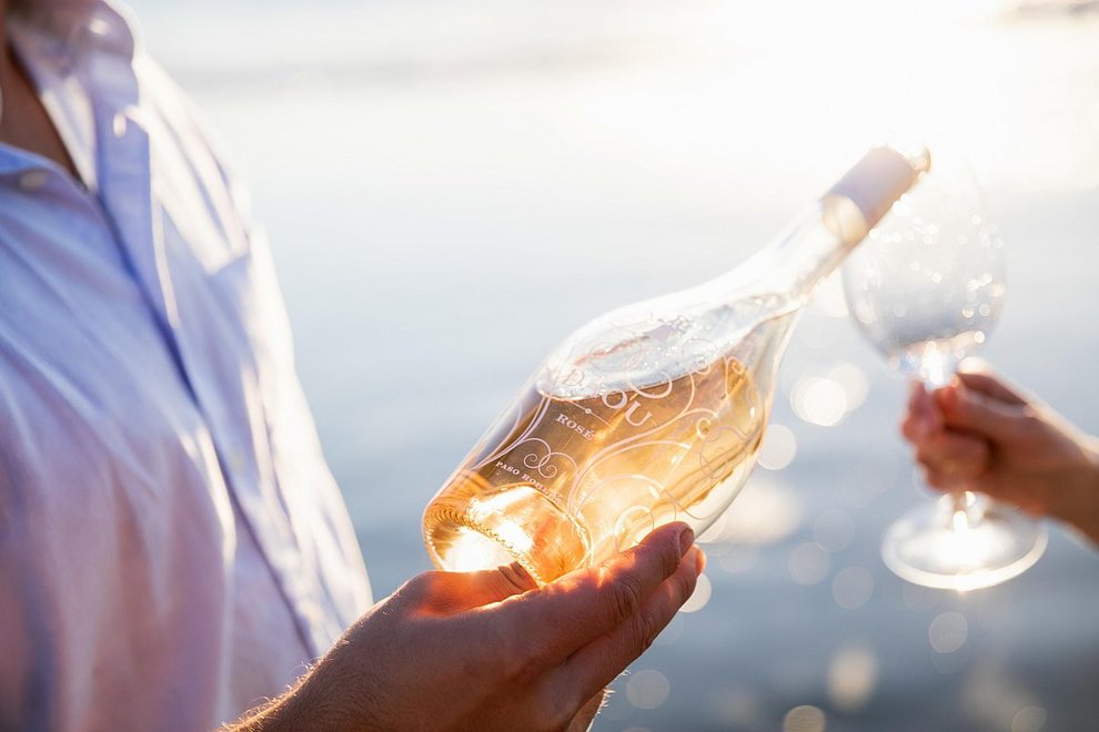 Person pouring a bottle of rosé into a glass in another person's hand