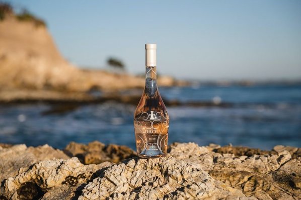 A bottle of DAOU Discovery rosé on rocks by the ocean