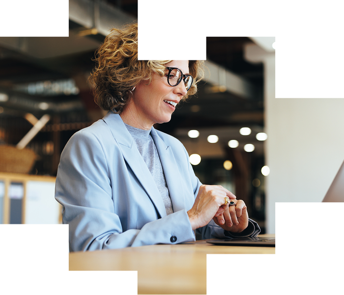 Woman with glasses and short curly hair working on her laptop