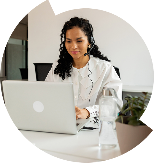 Close-up of a woman wearing a headset and working on a laptop. 