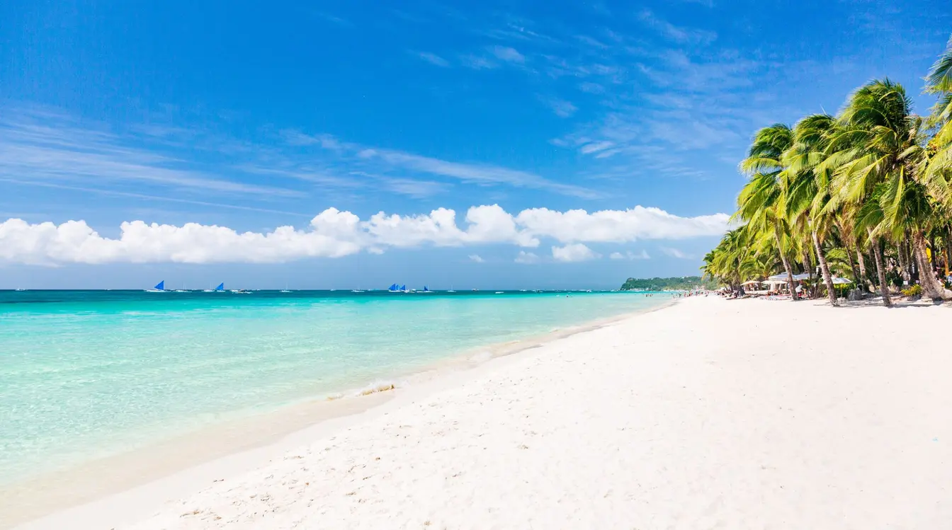 View of the powdery white sand, turquoise ocean and palm trees at White Beach on Boracay.