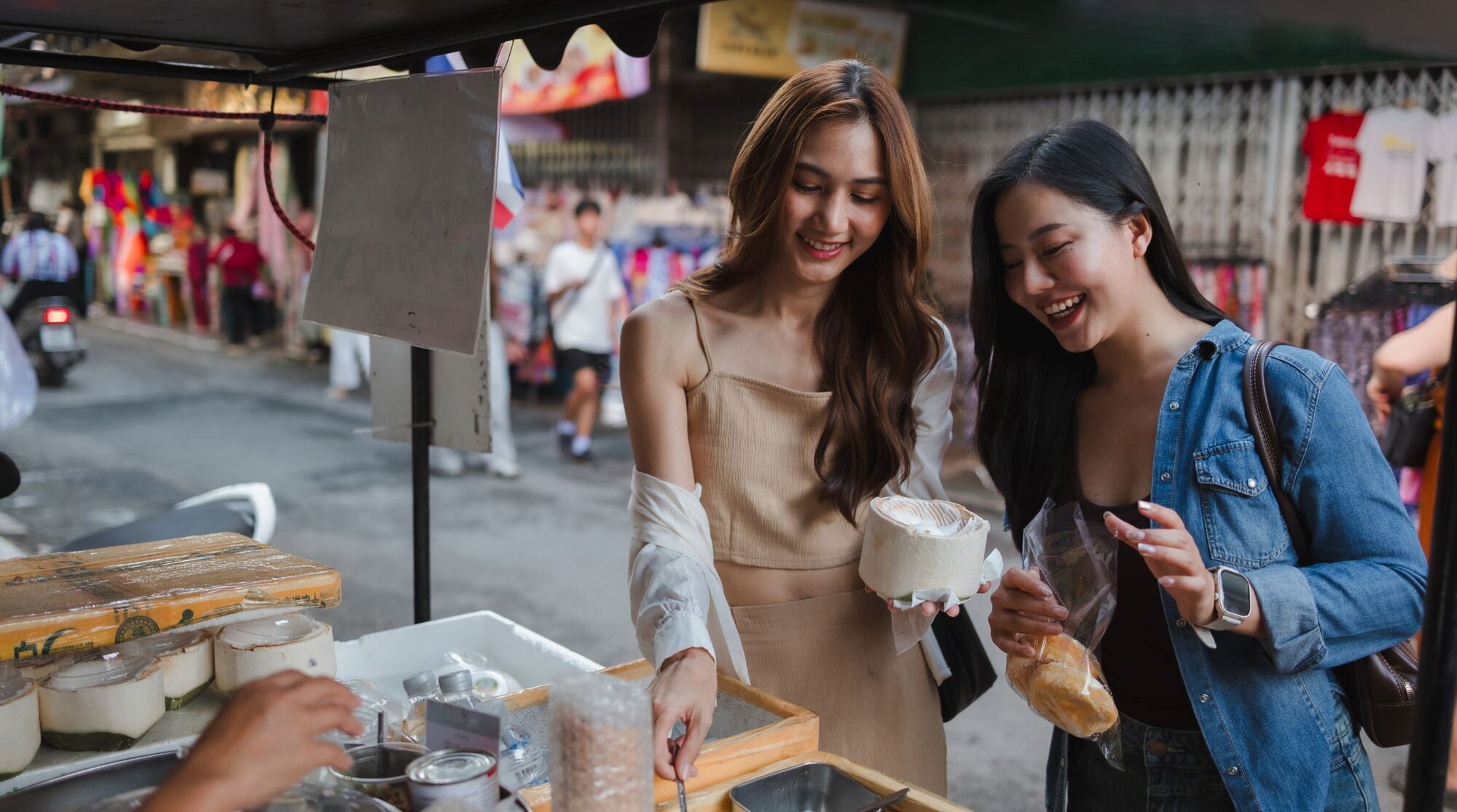 Zwei Touristinnen bezahlen in China ihr Essen auf einem Markt