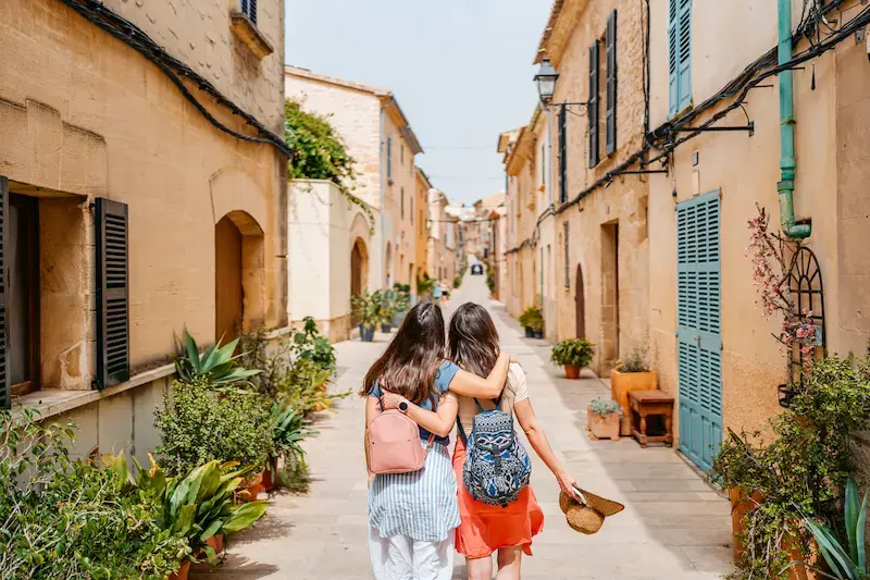 Dos amigas caminando por una calle tradicional en Mallorca durante un viaje.