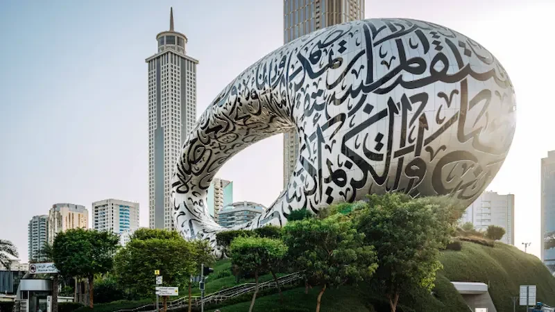 The silver and black torus-shaped, pillarless structure of Dubai's Museum of the Future as seen from the exterior against the city's skyline. 