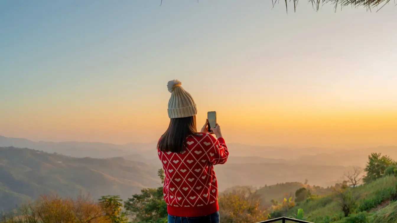 タイ北部の山頂で朝焼けの写真をスマートフォンで撮る女性観光客