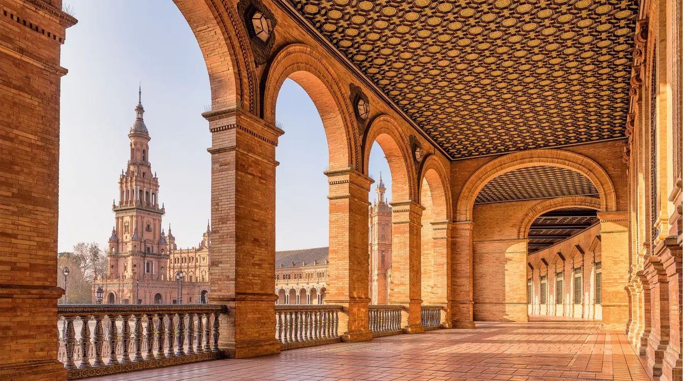 Vue panoramique de la Plaza de España à Séville, avec son canal, ses ponts et son architecture en briques et céramiques.