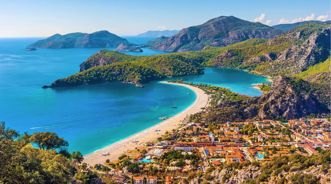 Vue aérienne de la plage d'Ölüdeniz en Turquie, avec son lagon turquoise, sa plage de sable et les montagnes environnantes.