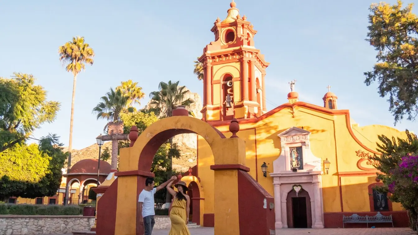 Pareja paseando frente a una iglesia en Ajijic, Jalisco, durante una excursión desde Guadalajara al lago de Chapala.