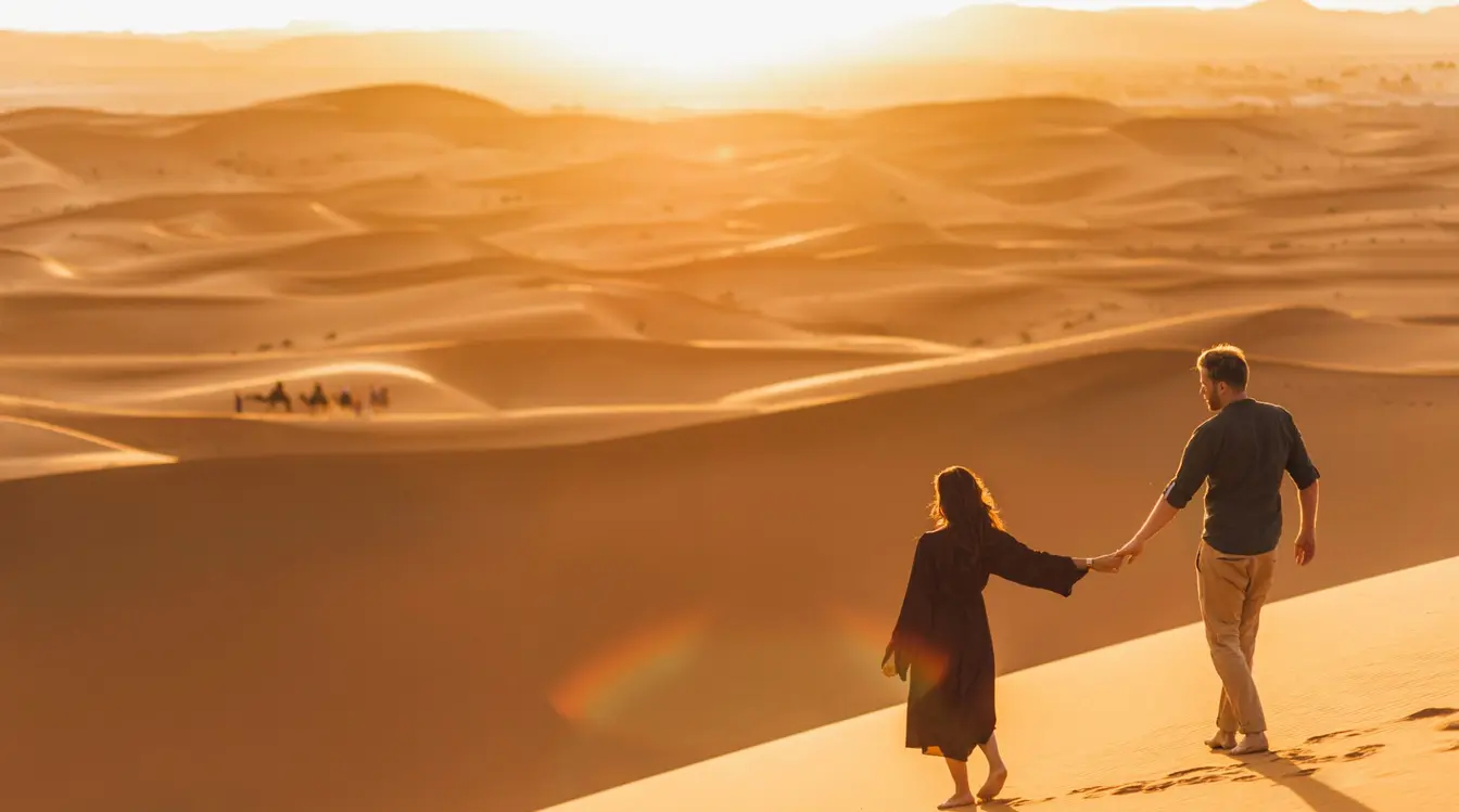 Coppia che cammina nel deserto al tramonto, vista da dietro, durante un viaggio avventura con paesaggio sabbioso.