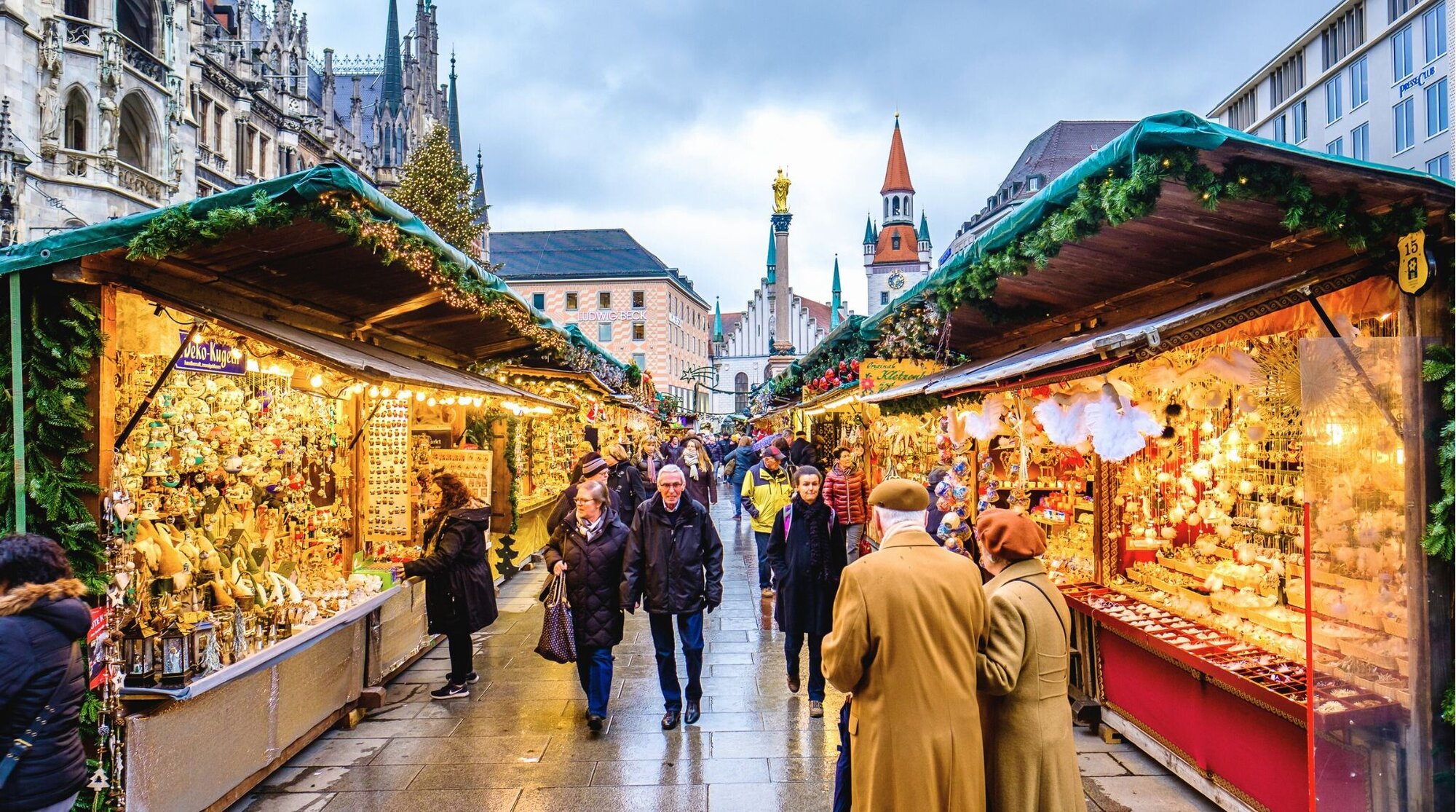 Pessoas passeando pelas barracas do mercado de Natal em Munique, Alemanha. O mercado de Natal de Munique acontece anualmente na Marienplatz e ruas adjacentes, famoso por seus vendedores de artesanato. A Antiga Prefeitura forma o pano de fundo na Marienplatz.