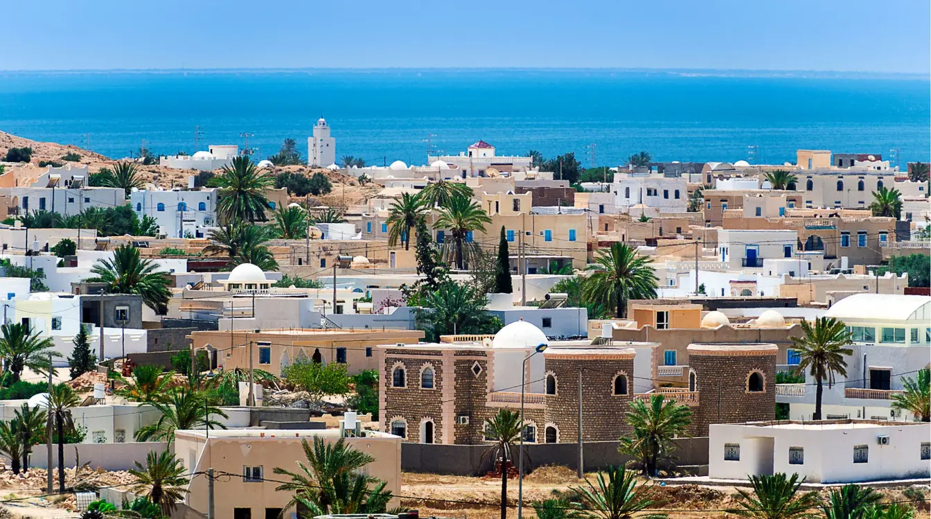 Vue sur le village de Guellala à Djerba, en Tunisie, avec ses maisons blanches, son minaret et la mer Méditerranée en arrière-plan.