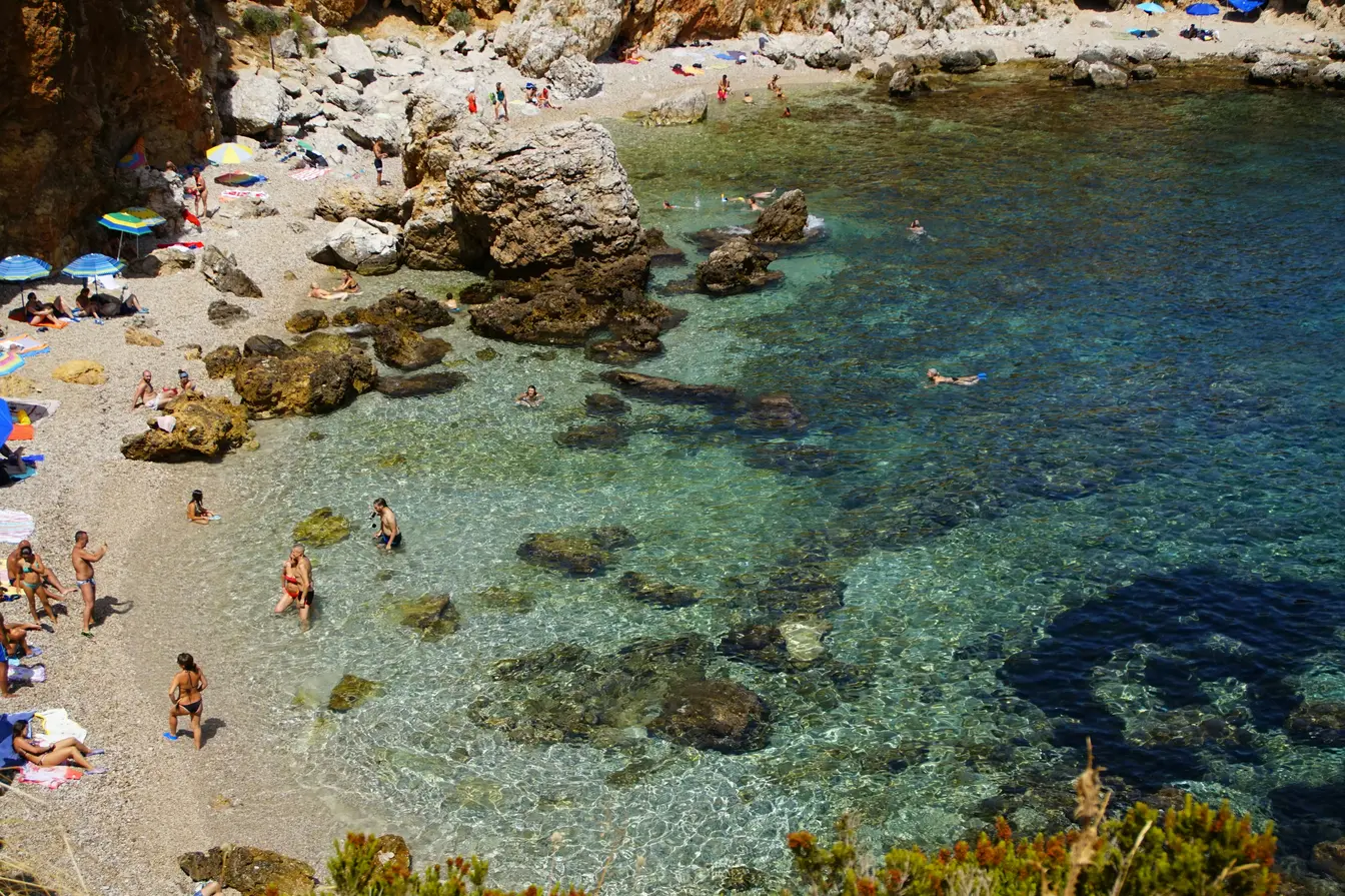 Spiaggia selvaggia della Riserva dello Zingaro, Sicilia, con mare cristallino e bagnanti