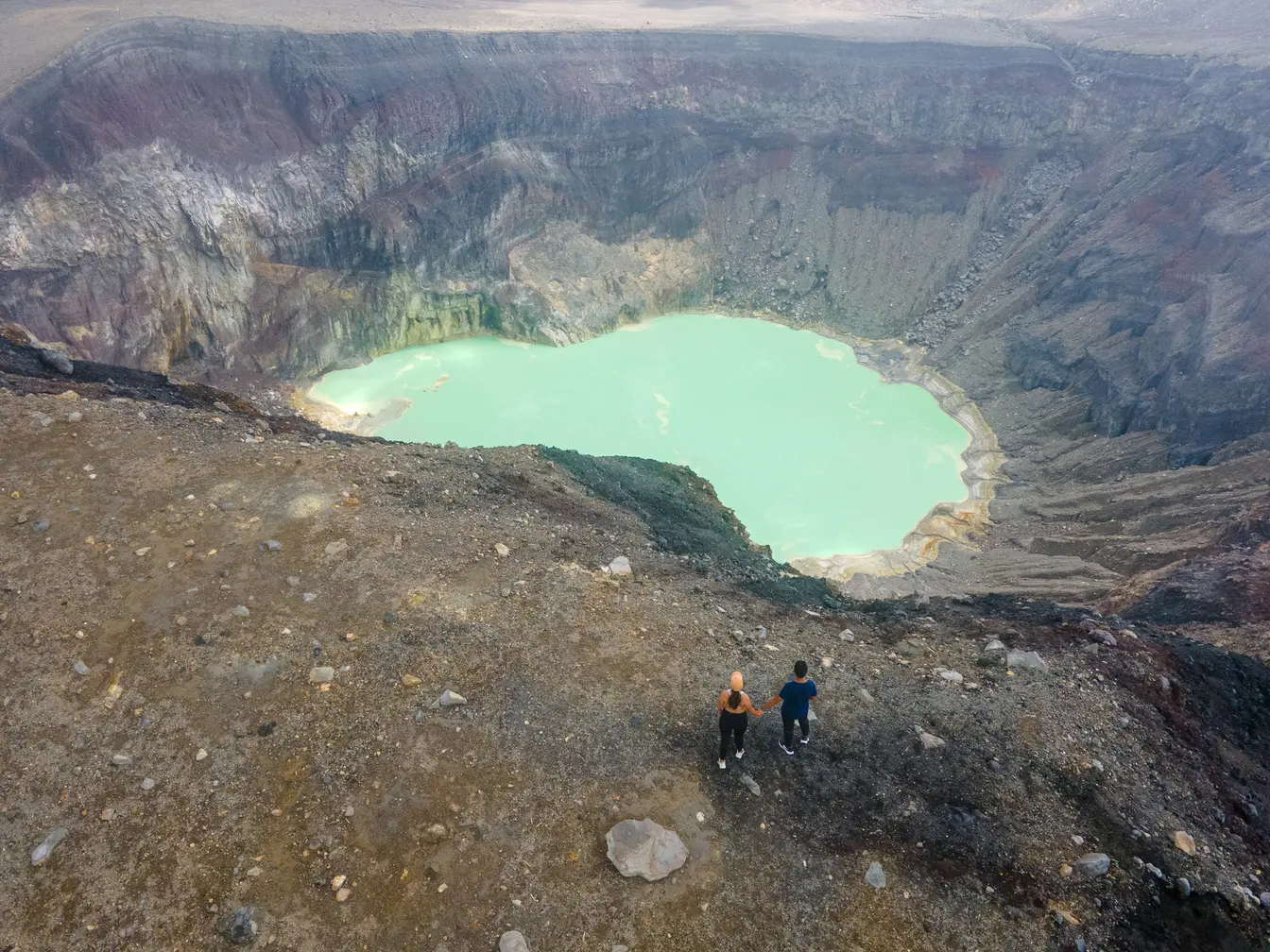 Couple holding hands at the turquoise crater lake at the summit of the Santa Ana Volcano Hike.
