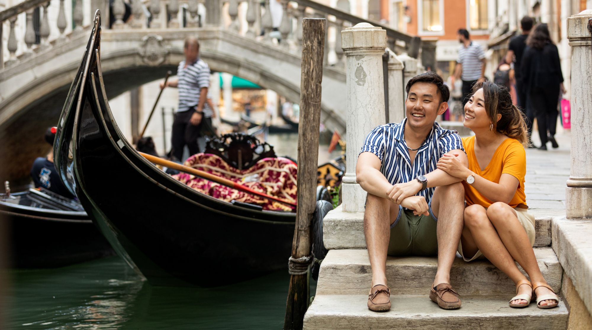 Eine Mann und Frau sitzen mit Internet in Italien an einem Kanal in Venedig am Wasser 