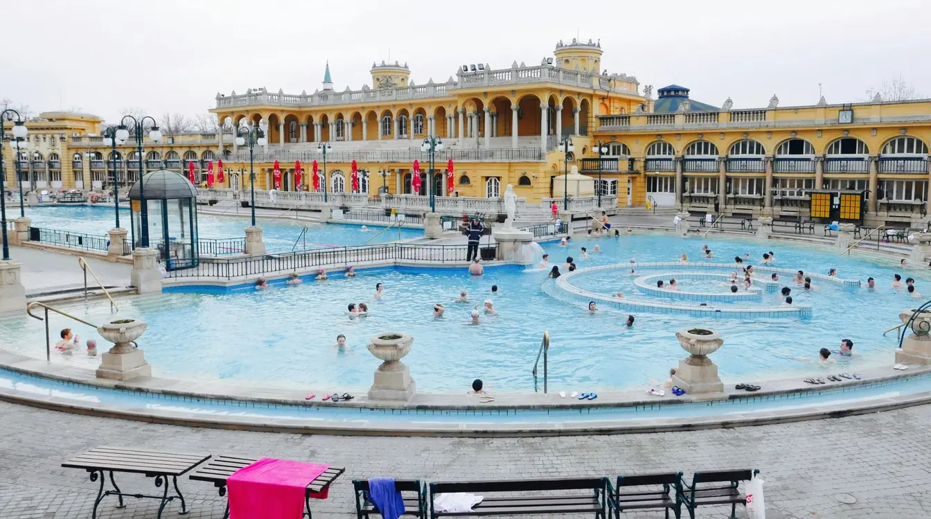 People swimming in the outdoor thermal pools at Széchenyi Baths in Budapest, Hungary.