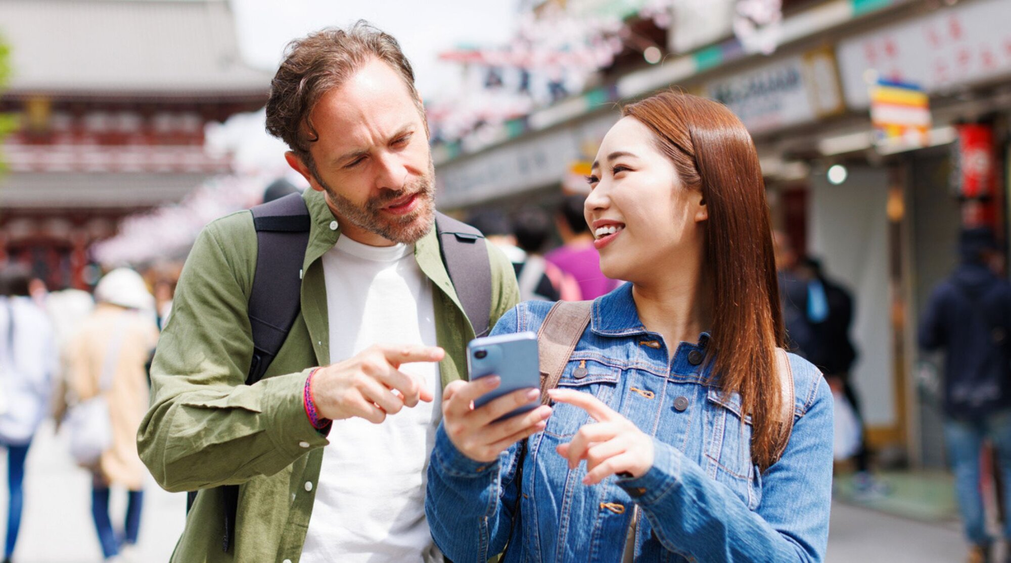Mann und Frau schauen gemeinsam auf ein Handy und nutzen Apps in Japan, um zu navigieren