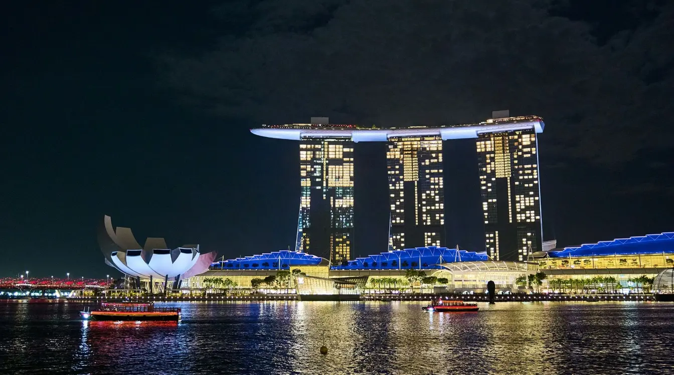 Night view across the Marina Bay waterfront featuring the Marina Bay Sands hotel and ArtScience Museum.