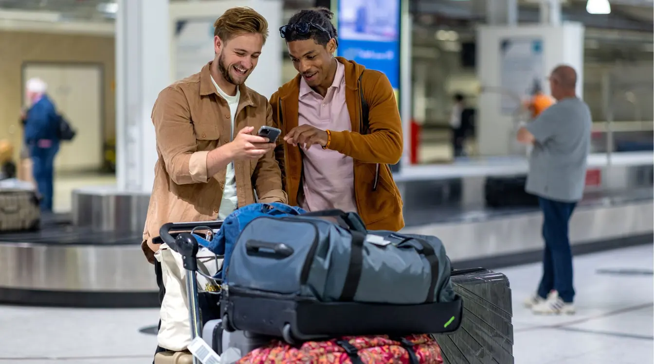 Voyageurs utilisant leur smartphone en attendant un vol à l’aéroport.