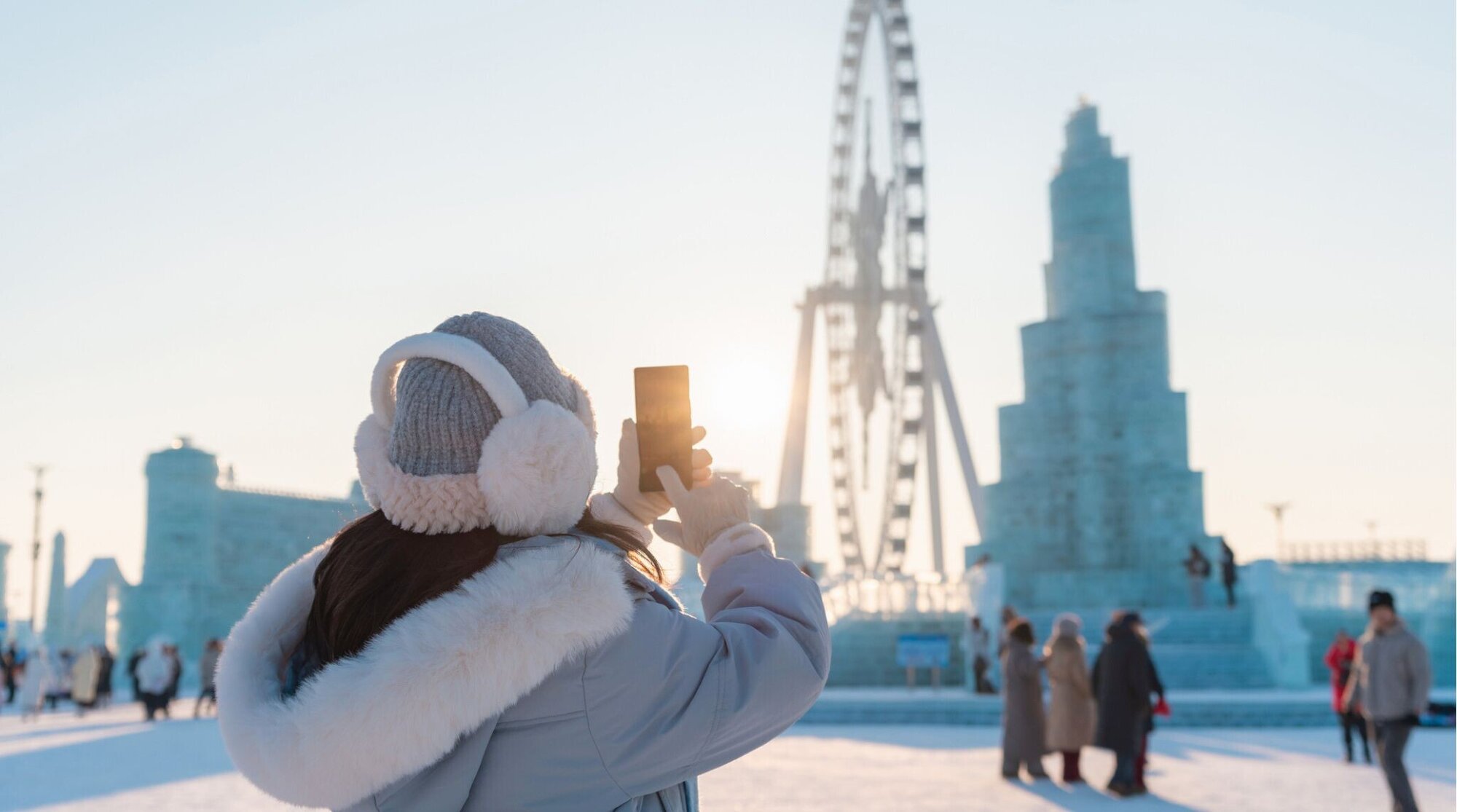 Turista jovem feliz tirando fotos e aproveitando o festival de gelo e neve em Harbin, China