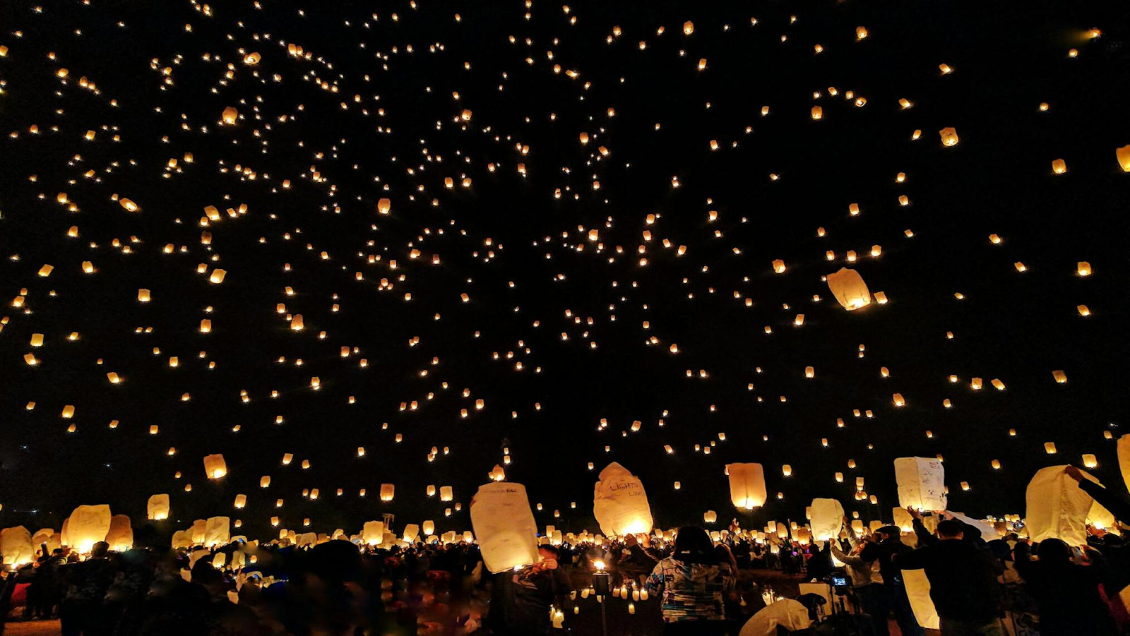 Many lanterns floating in the sky at nightime
