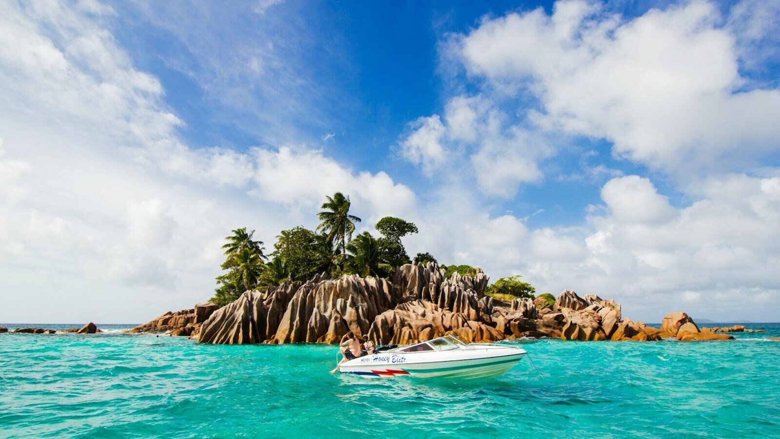 A small white boat on a body of water surrounded by trees and rocks during the daytime