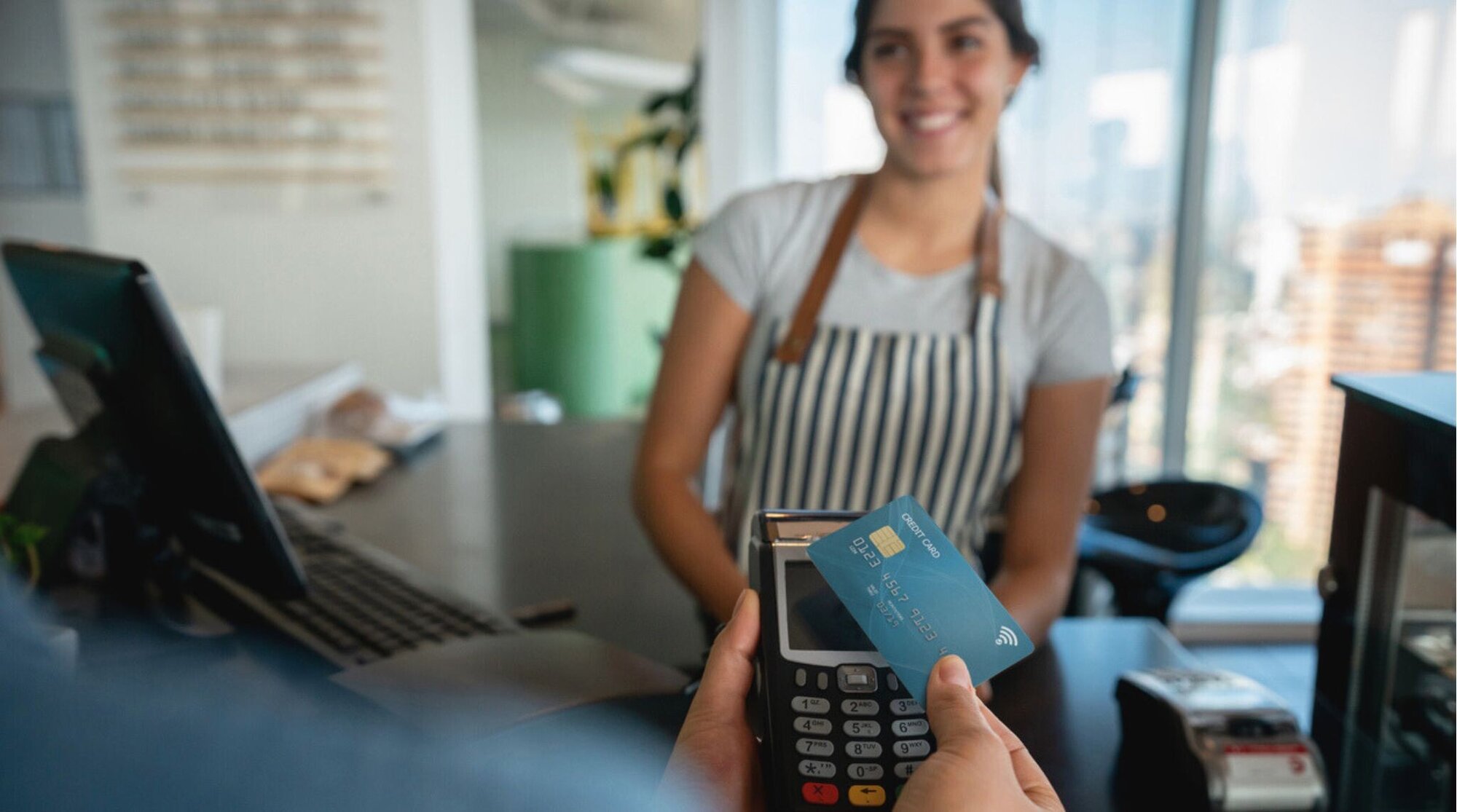 Cliente não identificada segurando um cartão de crédito e leitor, realizando um pagamento por contato, enquanto uma caixa amigável sorri em Santiago, Chile.