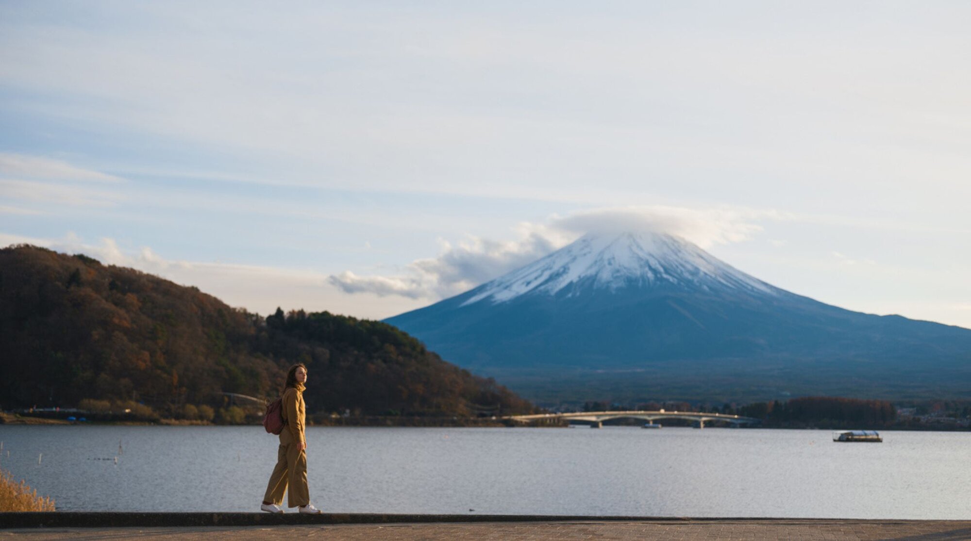 Gelassene Frau, die am Ufer des Kawaguchiko-Sees in Japan spaziert und den Fuji-Berg betrachtet