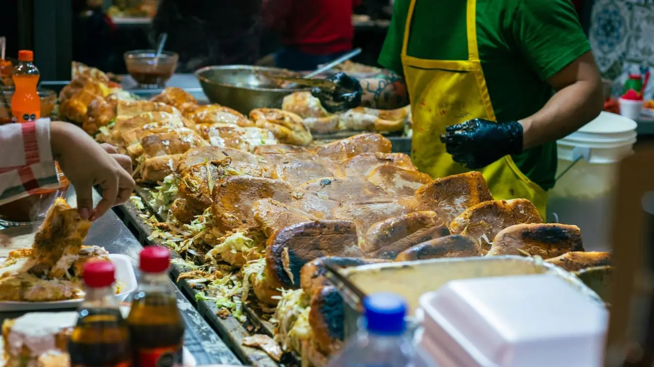 Puesto de comida en Guadalajara preparando tortas ahogadas y antojitos típicos dentro de un mercado local.