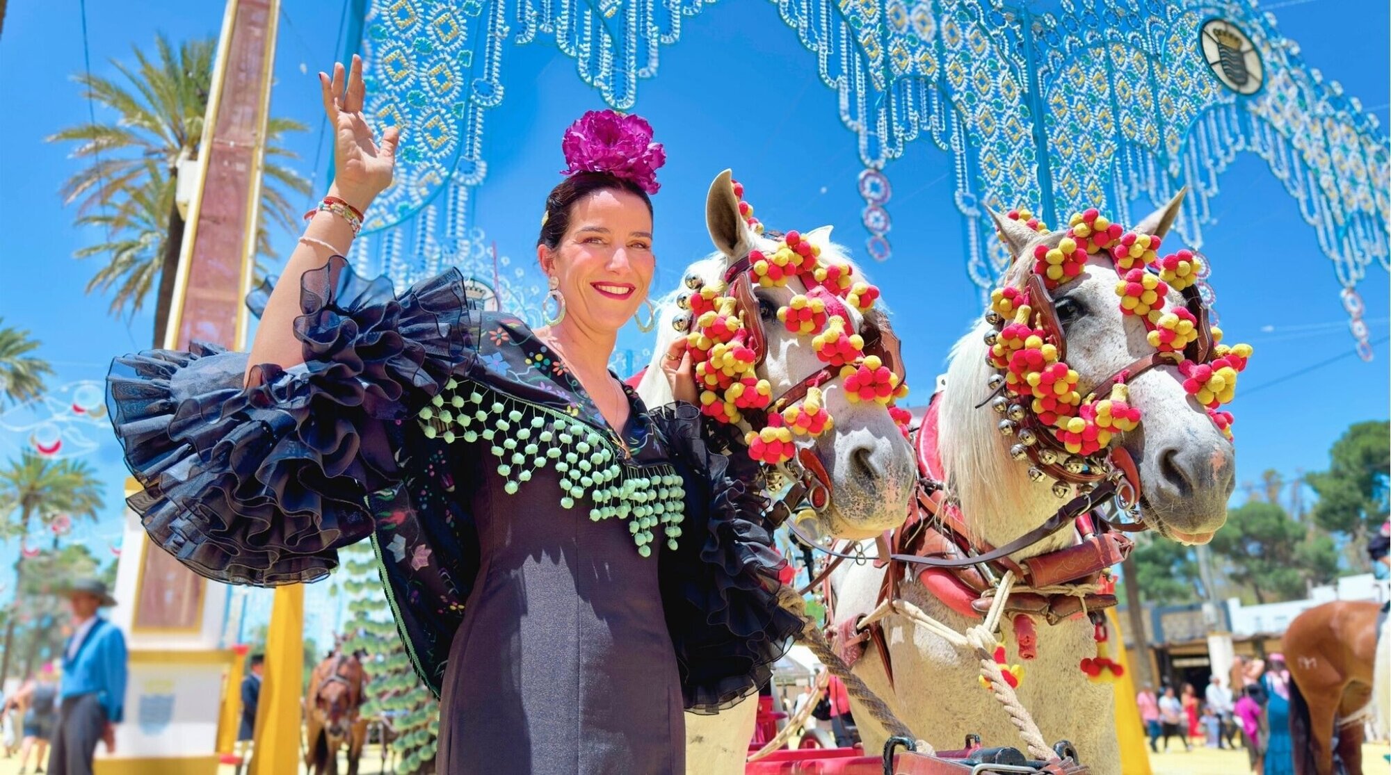 Mujer con traje tradicional junto a carruaje en la Feria de Sevilla, España.