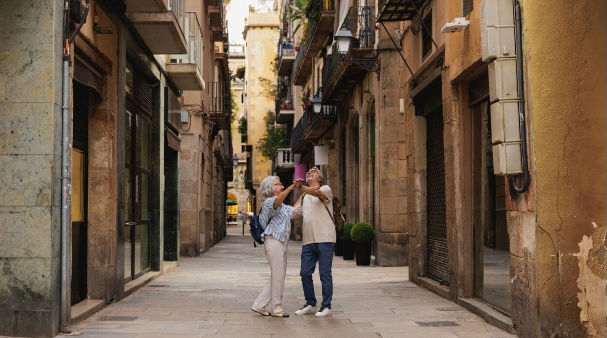 Turistas mayores bailando en un callejón estrecho del centro de Barcelona