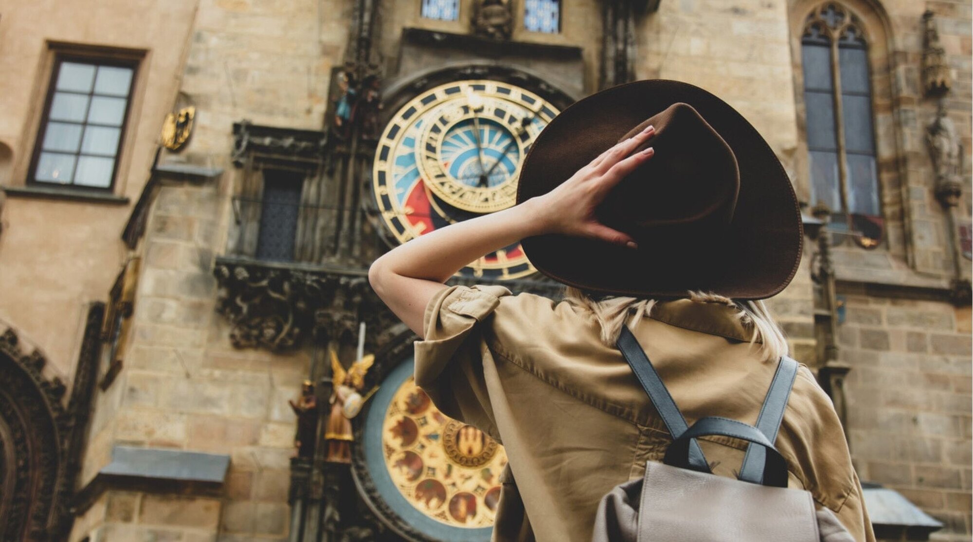Garota loira com chapéu e mochila perto do famoso relógio em Praga, República Tcheca.