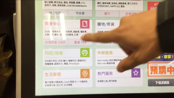 Man pointing at a TRA ticket booking option on the screen of an ibon ticket machine in 7-Eleven.