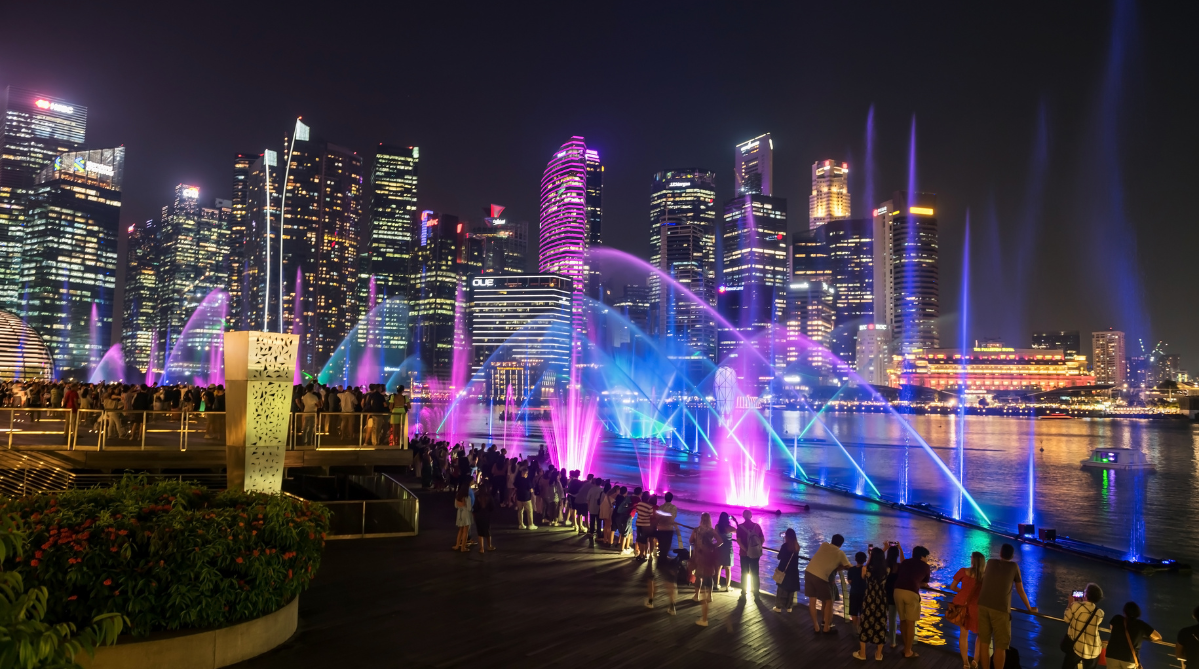 People at Marina Bay Sands enjoy the Spectra show with the modern buildings of the Central Business District in the backdrop