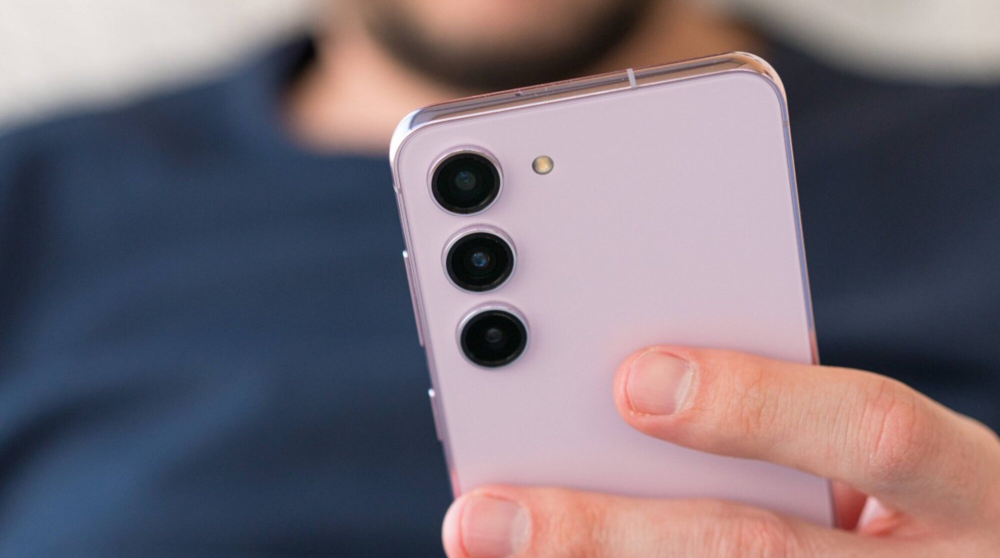 יד אוחזת בטלפון סמסונג s23 ורוד