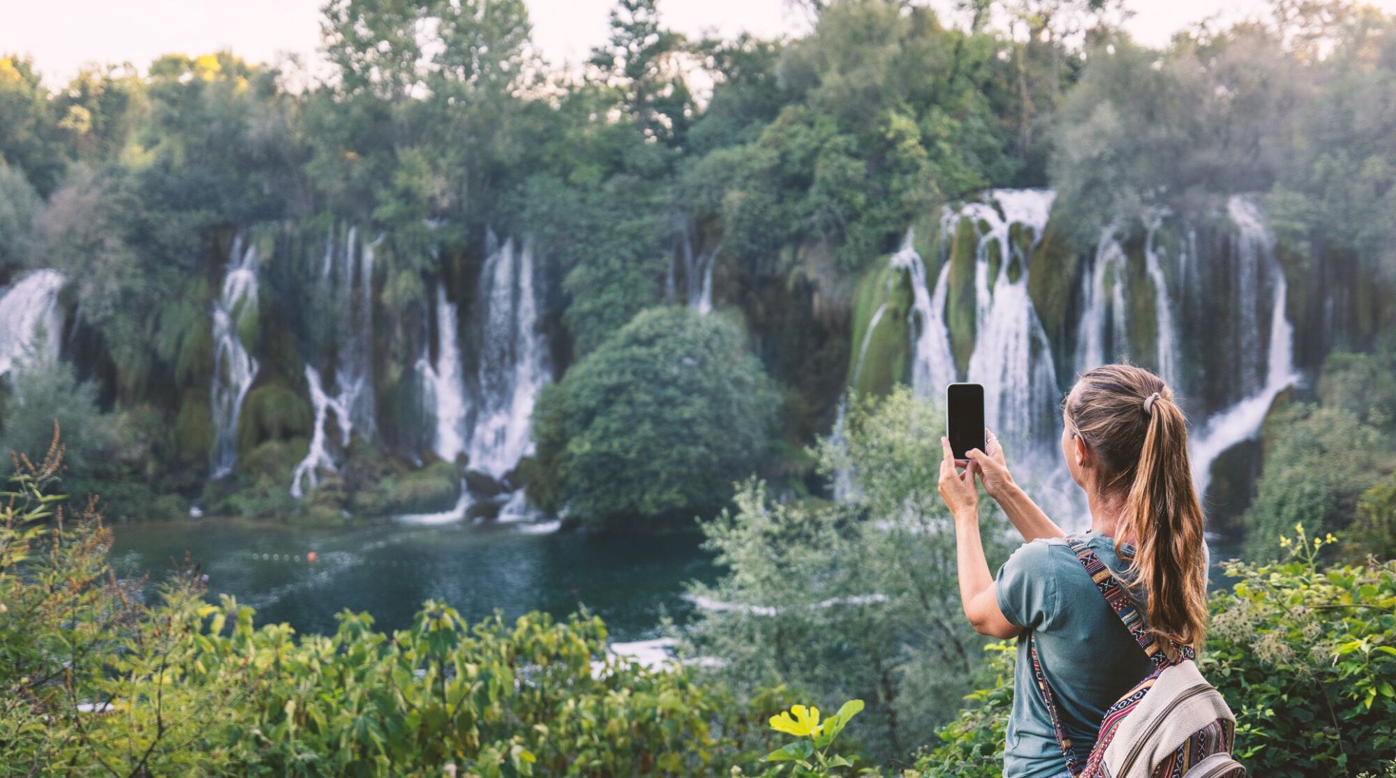 Frau Fotografiert Malerische Wasserfälle mit einer eSIM in Bosnien und Herzegowina