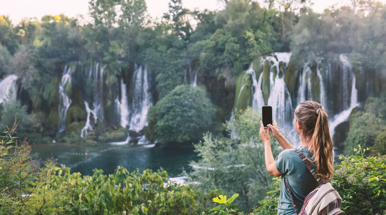 Frau Fotografiert Malerische Wasserfälle mit einer eSIM in Bosnien und Herzegowina