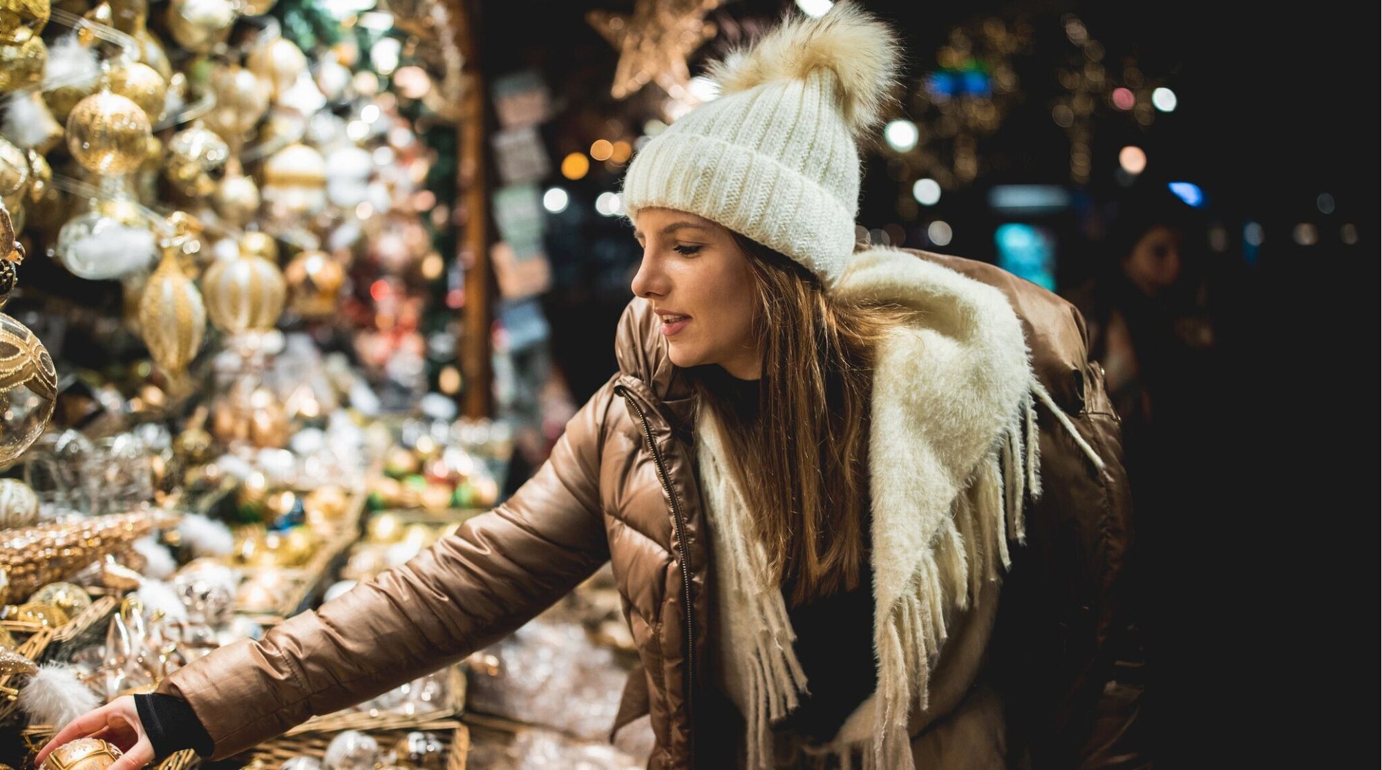 Mulher jovem procurando enfeites de Natal em uma feira de rua natalina