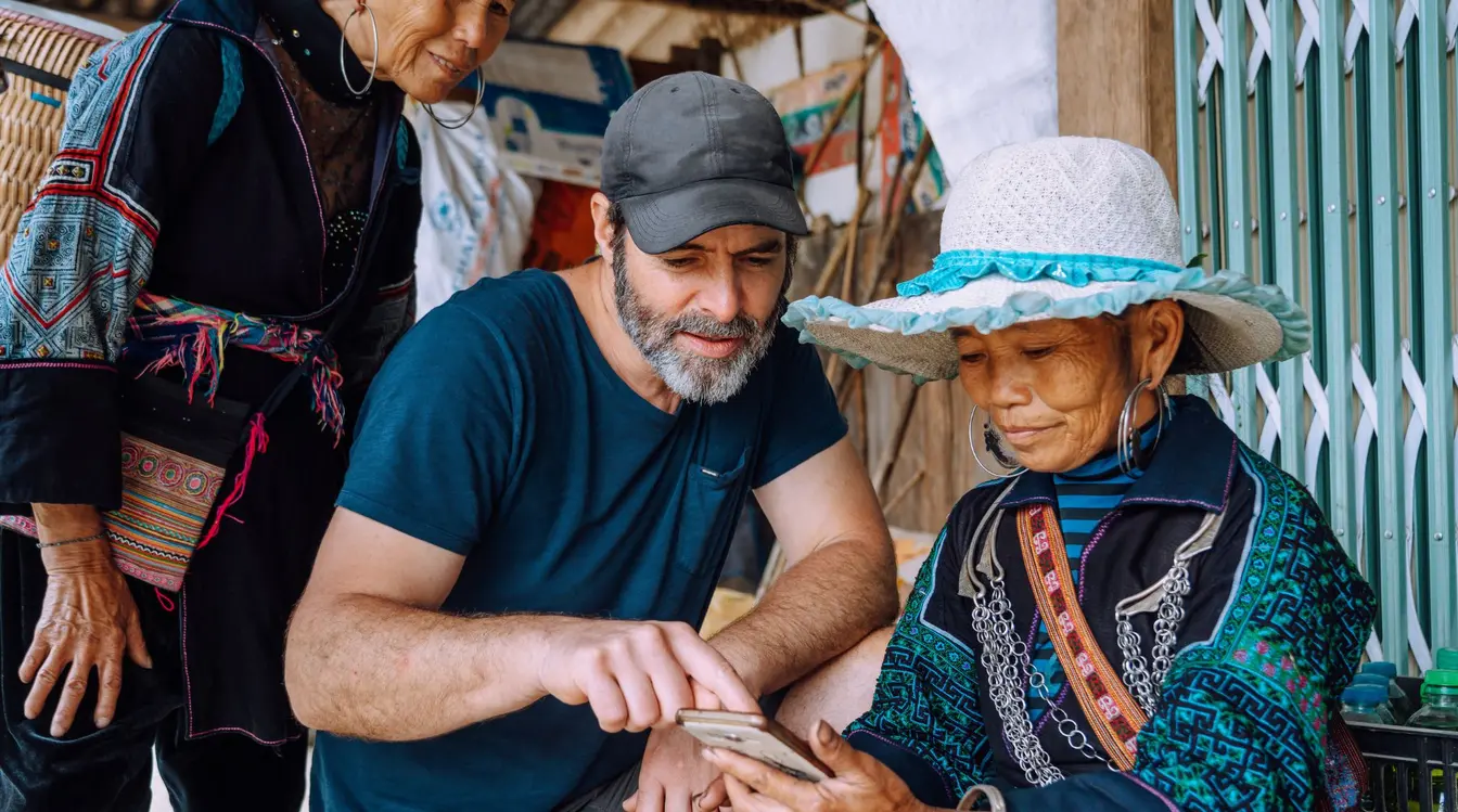 Zwei Frauen sprechen über eine App in Vietnam mit einem Touristen