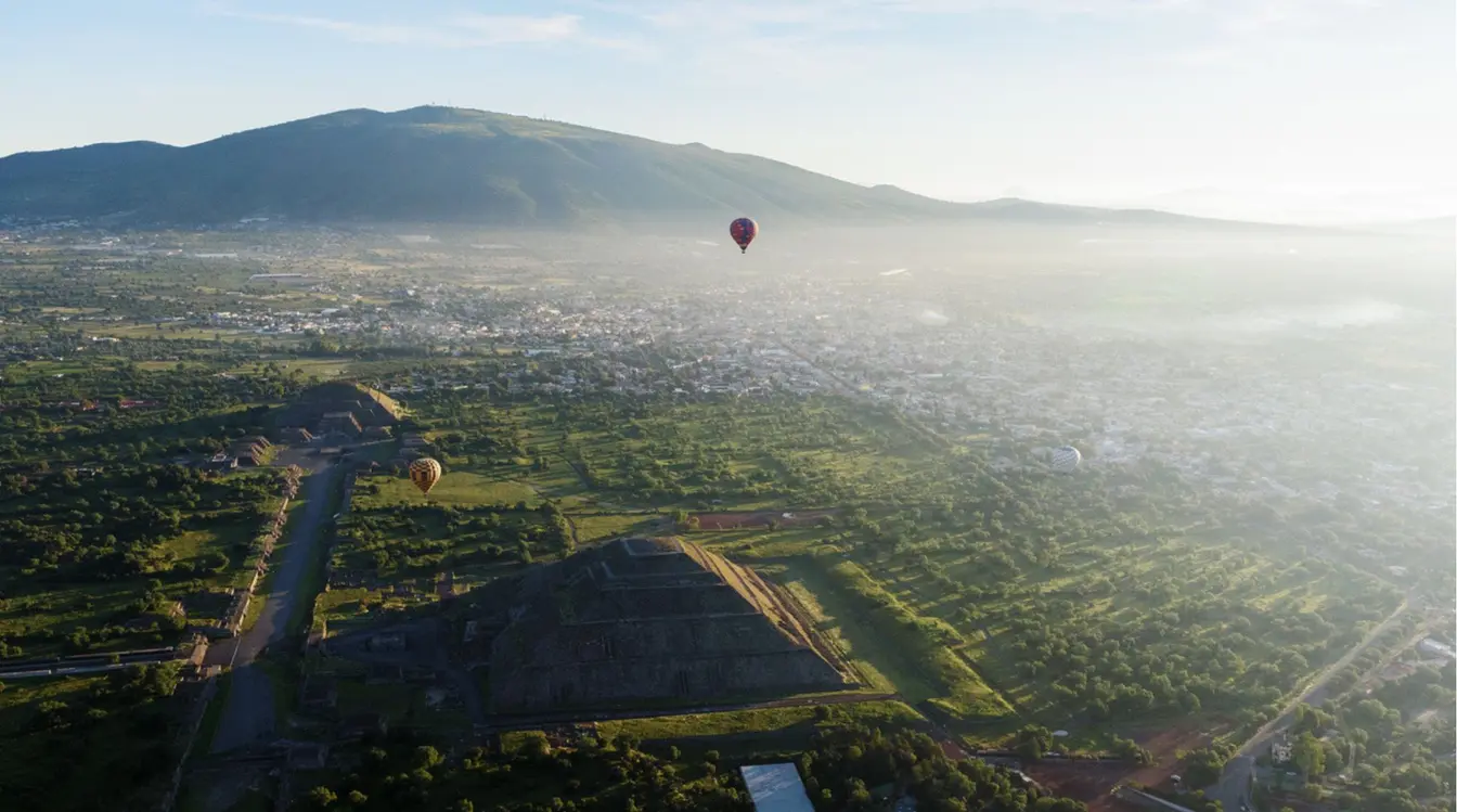 Globo aerostático volando sobre Teotihuacán al amanecer con las pirámides visibles desde el aire