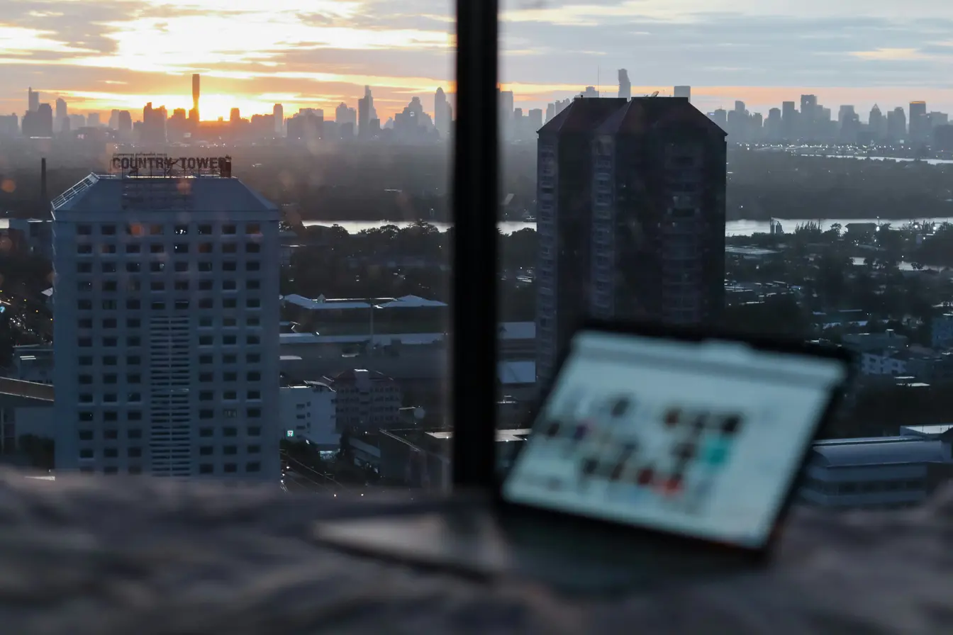 Imagen de un portátil en primer plano que muestra una panorámica de Bangkok al anochecer para ilustrar el teletrabajo.
