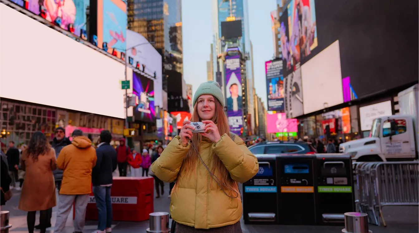  Jovem turista influencer na Times Square, ponto turístico de Nova York, com máquina fotográfica analógica pronta para registrar sua viagem.