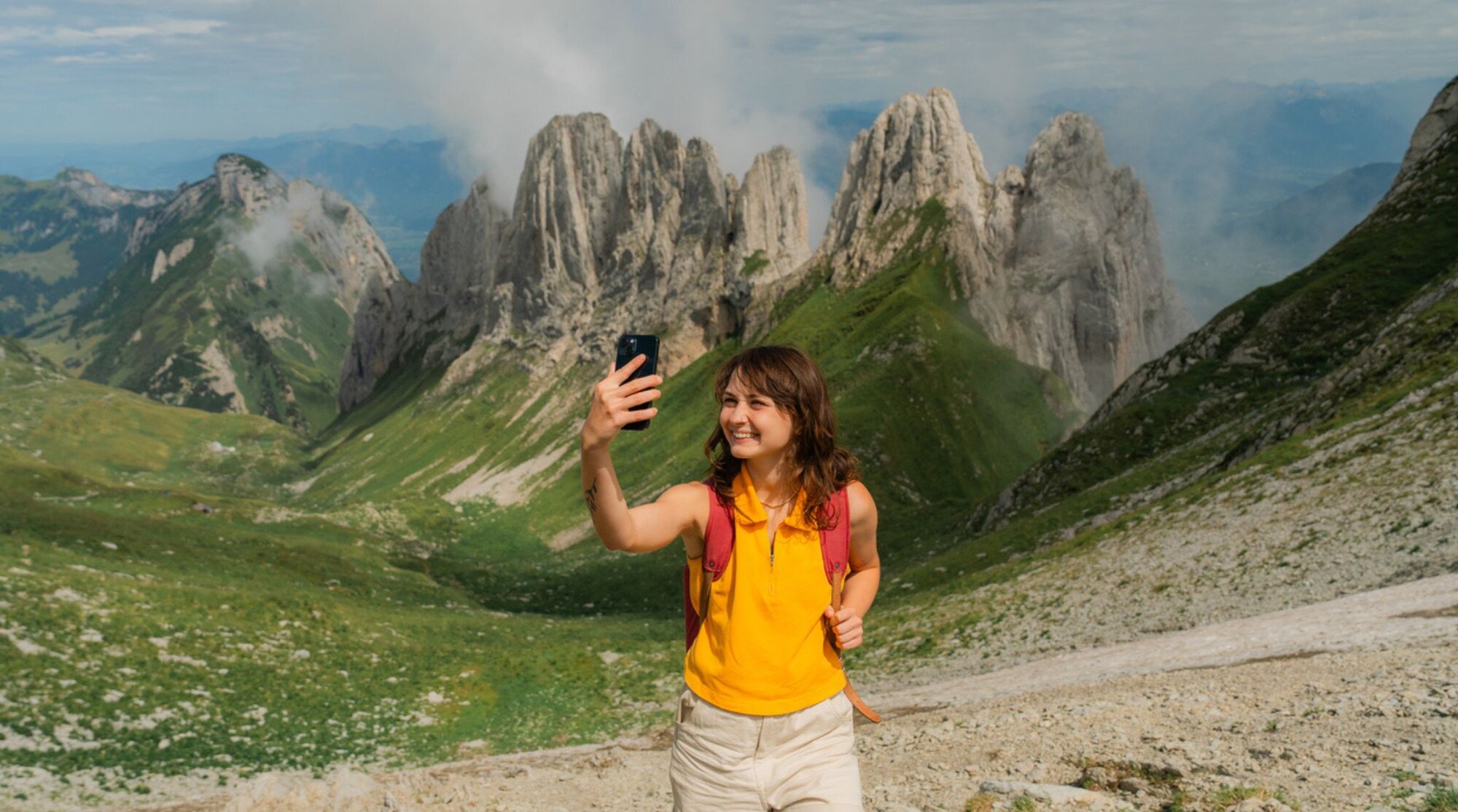 Frau mit einer eSIM macht Selfie auf einer Wanderung in den Appenzeller Alpen in der Schweiz